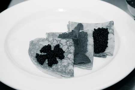 Pancakes with caviar on a white plate. Selective focus. Shallow depth of field. Toned.の写真素材