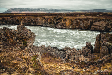 Water of the Godafoss Waterfall - beautiful part of stony rocky desert landscape of Iceland. Toned.