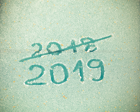 Inscription 2019 and crossed out 2018 on the glass by hoarfrost.の写真素材