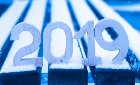 Wooden figures 2019 on the snowy bench. New year and christmas theme. Toned.