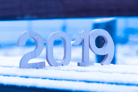 Wooden figures 2019 on the snowy bench. New year and christmas theme. Toned.