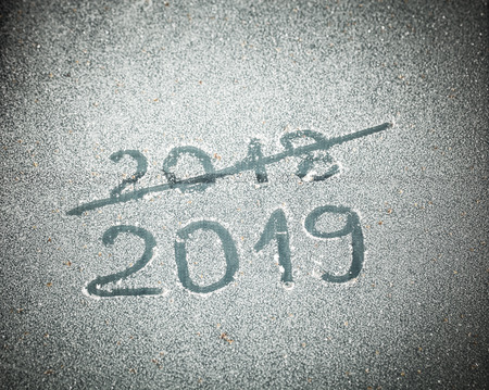Inscription 2019 and crossed out 2018 on the glass by hoarfrost.の写真素材