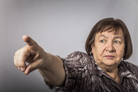 Portrait of an elderly woman pointing at something with your finger. Toned.の写真素材