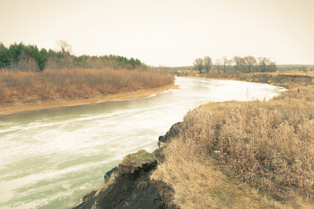 Frozen river with snow and ice in the autumn landscape. Toned.