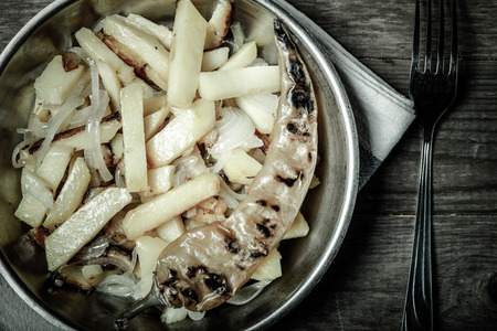 Delicious roast potatoes with onion and spices in a pan on kitchen towel on the old wooden table....