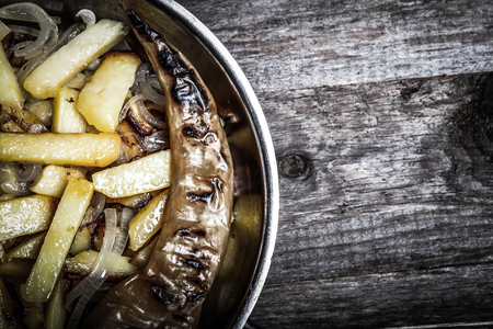 Delicious roast potatoes with onion and spices in a pan on kitchen towel on the old wooden table. Traditional rural dinner. Toned.の写真素材