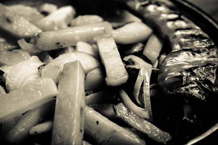 Delicious roast potatoes with onion and spices in a pan on kitchen towel on the old wooden table....