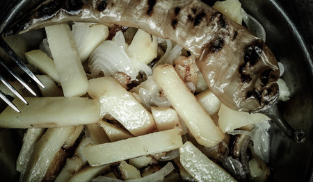 Delicious roast potatoes with onion and spices in a pan on kitchen towel on the old wooden table....