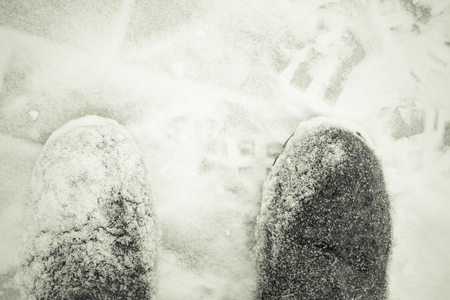 Legs of old woman wich clears a snowdrifts with a snow shovel. Toned.の写真素材