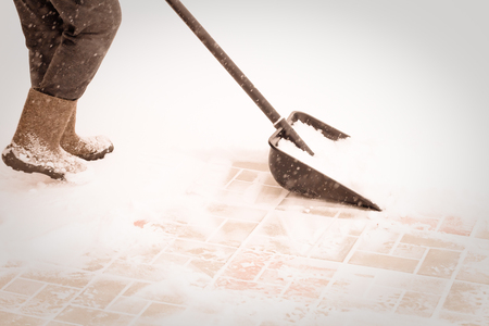 Legs of old woman wich clears a snowdrifts with a snow shovel. Toned.の写真素材