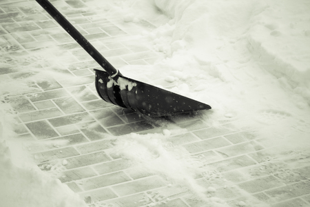 Snow shovel on a tile ground. Toned.の写真素材