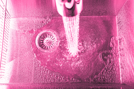 Flow of water in a metal sink on a modern kitchen. Toned.の写真素材