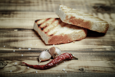 Grilled bread on burned wooden table. Preparing for traditional rural dinner. Toned.の写真素材