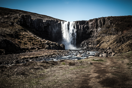 Famous Iceland waterfalls with a clean water on a stony rocky mountain landscape. Toned.の写真素材