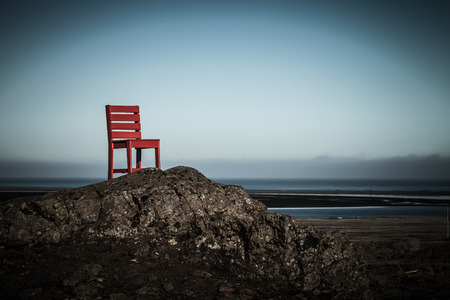 Red wooden chair on a empty stony landscape in Iceland. Toned.の写真素材