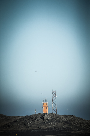 Technical building and metal tower on a hill on the coast. Iceland fjords. Toned.の写真素材