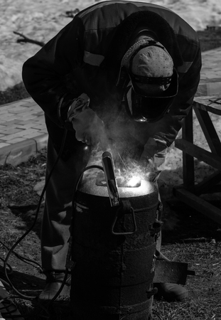 An experienced welder at work. Preparation and welding process of cast iron furnace. Selection focus. Shallow depth of field. Toned.の写真素材