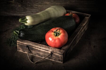 Fresh vegetables in a burned rustic texture box for background. Rough weathered wooden board. Toned.の写真素材