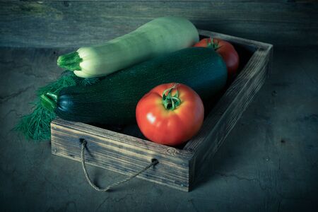 Fresh vegetables in a burned rustic texture box for background. Rough weathered wooden board. Toned.の写真素材