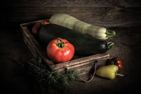 Fresh vegetables in a burned rustic texture box for background. Rough weathered wooden board. Toned.の写真素材