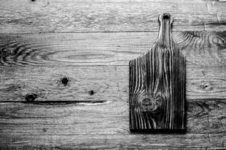 Handmade burned cutting board on a wooden rustic texture for background. Rough weathered wooden board. Toned.の写真素材