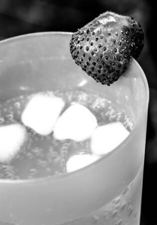 Glass with sparkling water and frash bright strawberries in a summer garden. Shallow depth of field. Selective focus. Toned.の写真素材