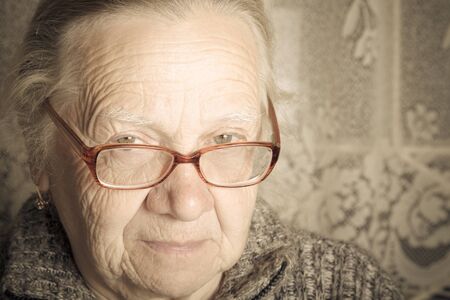 Elderly woman with glasses in rustic interior. Toned.の写真素材