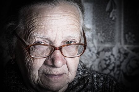 Elderly woman with glasses in rustic interior. Toned.の写真素材