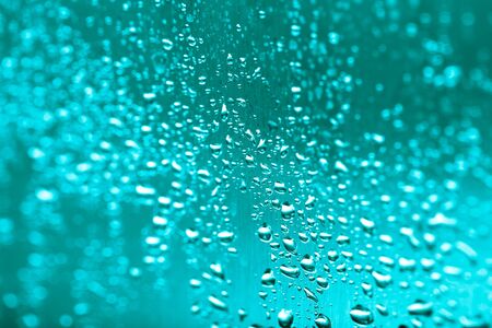 Drops of water on a glass background. Green. Selective focus. Toned.