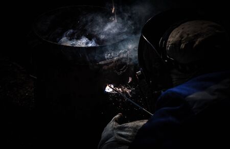 An experienced welder at work. Preparation and welding process of cast iron furnace. Selection focus. Shallow depth of field. Toned.の写真素材