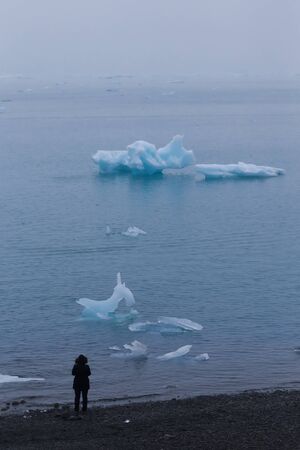 Girl watching bizarre ice floes of Iceberg lagoon jokulsarlon on the south of Iceland.