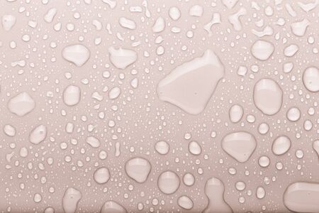 Drops of water on a color background. Selective focus. Beige. Toned.