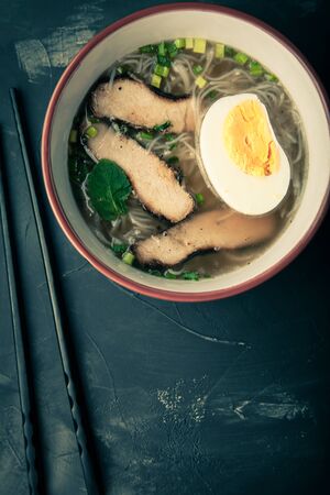 Composition with a bowl of rice noodles, meat and vegetables. Toned.