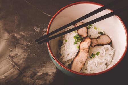 Composition with a bowl of rice noodles, meat and vegetables. Toned.の写真素材