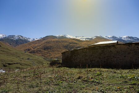 Old stone houses and fences of the village of Ushguli in a beautiful autumn landscape with white...