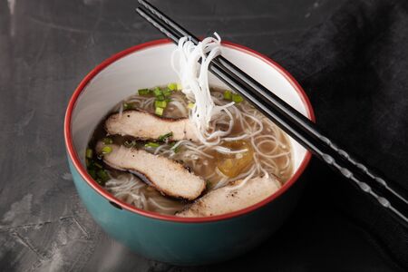 Composition with a bowl of rice noodles, meat and vegetables.の写真素材