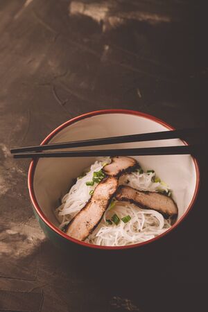 Composition with a bowl of rice noodles, meat and vegetables. Toned.の写真素材