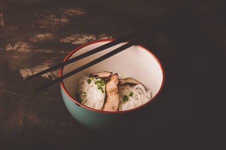 Composition with a bowl of rice noodles, meat and vegetables. Toned.の写真素材