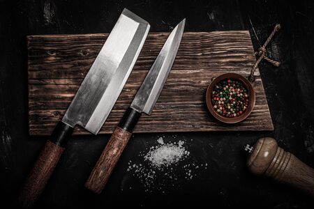 Chopping knives and spices on a dark table. Toned.