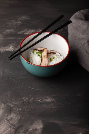 Composition with a bowl of rice noodles, meat and vegetables.の写真素材