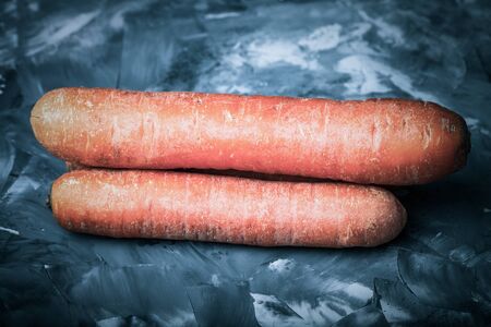 Composition with a carrot on a textured plastered surface. Toned.