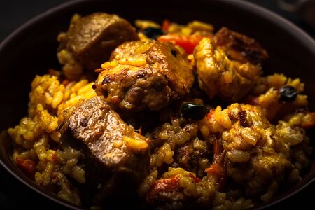 Large portion of pilaf in a clay dish. Delicious uzbek homemade meal. Toned.の写真素材