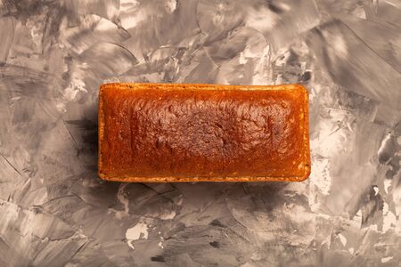 Composition with a bread on a textured plastered surface.