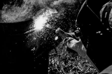 An experienced welder at work. Preparation and welding process of cast iron furnace. Selection focus. Shallow depth of field. Toned.の写真素材