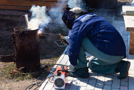 An experienced welder at work. Preparation and welding process of cast iron furnace. Selection...