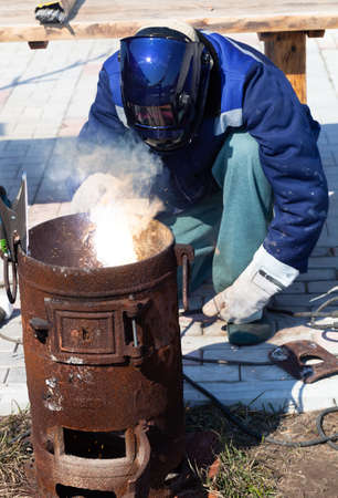 An experienced welder at work. Preparation and welding process of cast iron furnace. Selection focus. Shallow depth of field.の写真素材