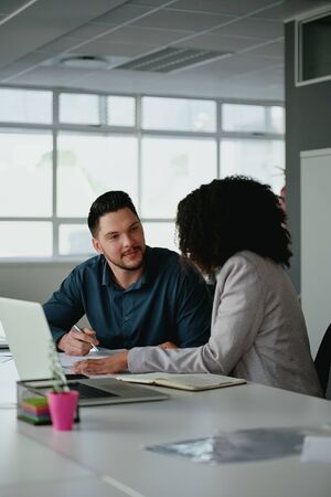 Young business team or partnership having a serious discussion at a table in the office