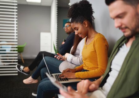 Concentrated smiling young african american woman sitting in queue preparing for job talk hiring in...
