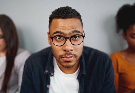 Portrait of a unemployed african american young man wearing eyeglasses waiting for the interview looking at cameraの写真素材