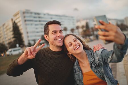 A happy friends having fun and taking a selfie on mobile phone, enjoying city lifeの写真素材